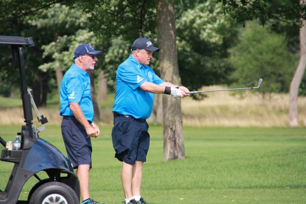 A blind golfer stands facing the direction he wishes to hit. He has his club in front of him and his coach is standing right behind him giving him directions. This is a very common technique for many blind golfers.
